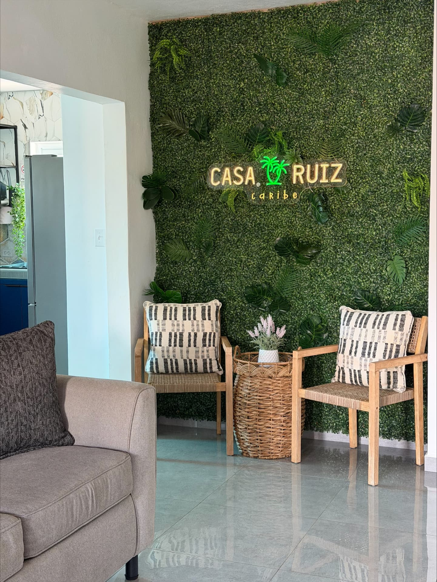 Living room seating beneath a green plant wall with the Casa Ruiz Caribe sign